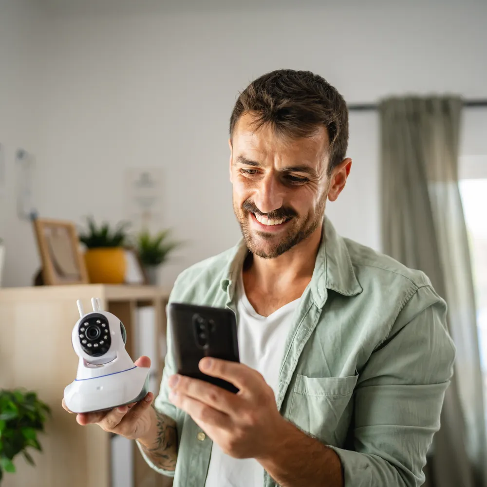 Homme souriant tenant une caméra de sécurité